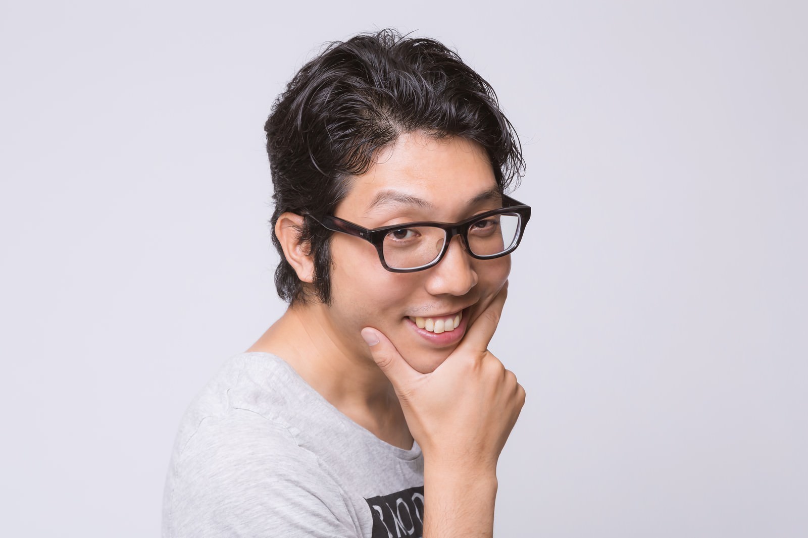眼鏡をかけた男性が顎に手を当てて推理する表情でポーズを取っている［モデル：紳さん］