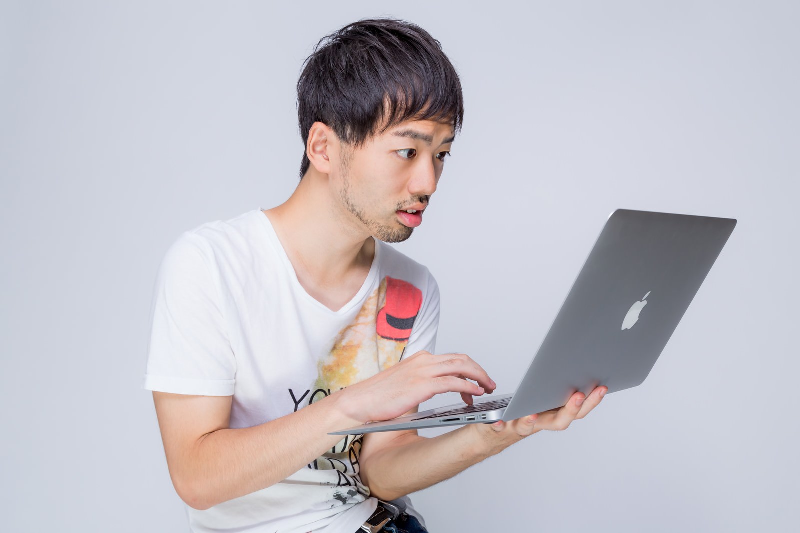 MBAを見て驚く男性、赤いイヤホンを首にかけている［モデル：ひろゆき］