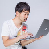 ノートパソコンを持って驚く男性の写真
