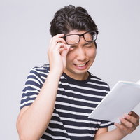 眼鏡を外して本を読む男性の写真