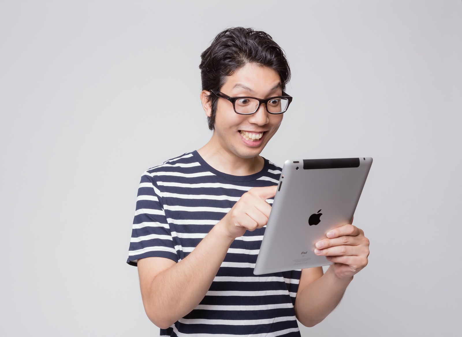 iPadを指差して笑うメガネの男性［モデル：紳さん］