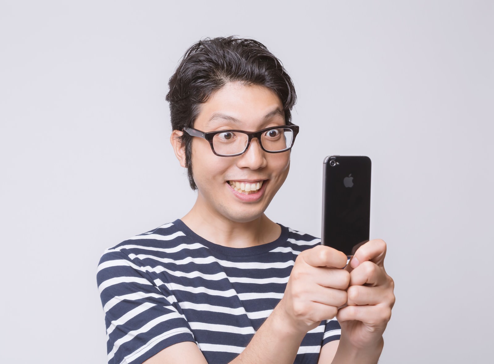 黒いiPhoneで自撮りをする眼鏡をかけた笑顔の男性［モデル：紳さん］