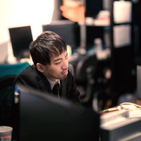 オフィスで孤独にパソコンで残業する男性の写真