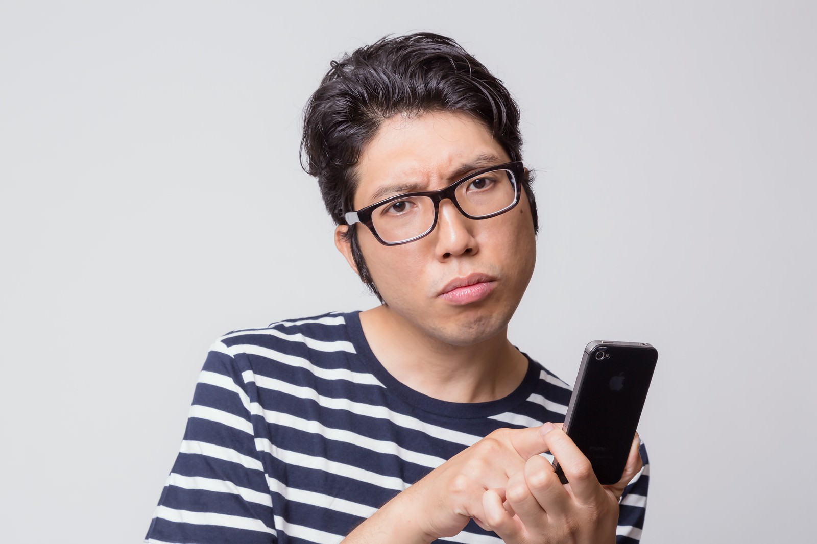 スマホを持ち困惑する眼鏡の男性［モデル：紳さん］