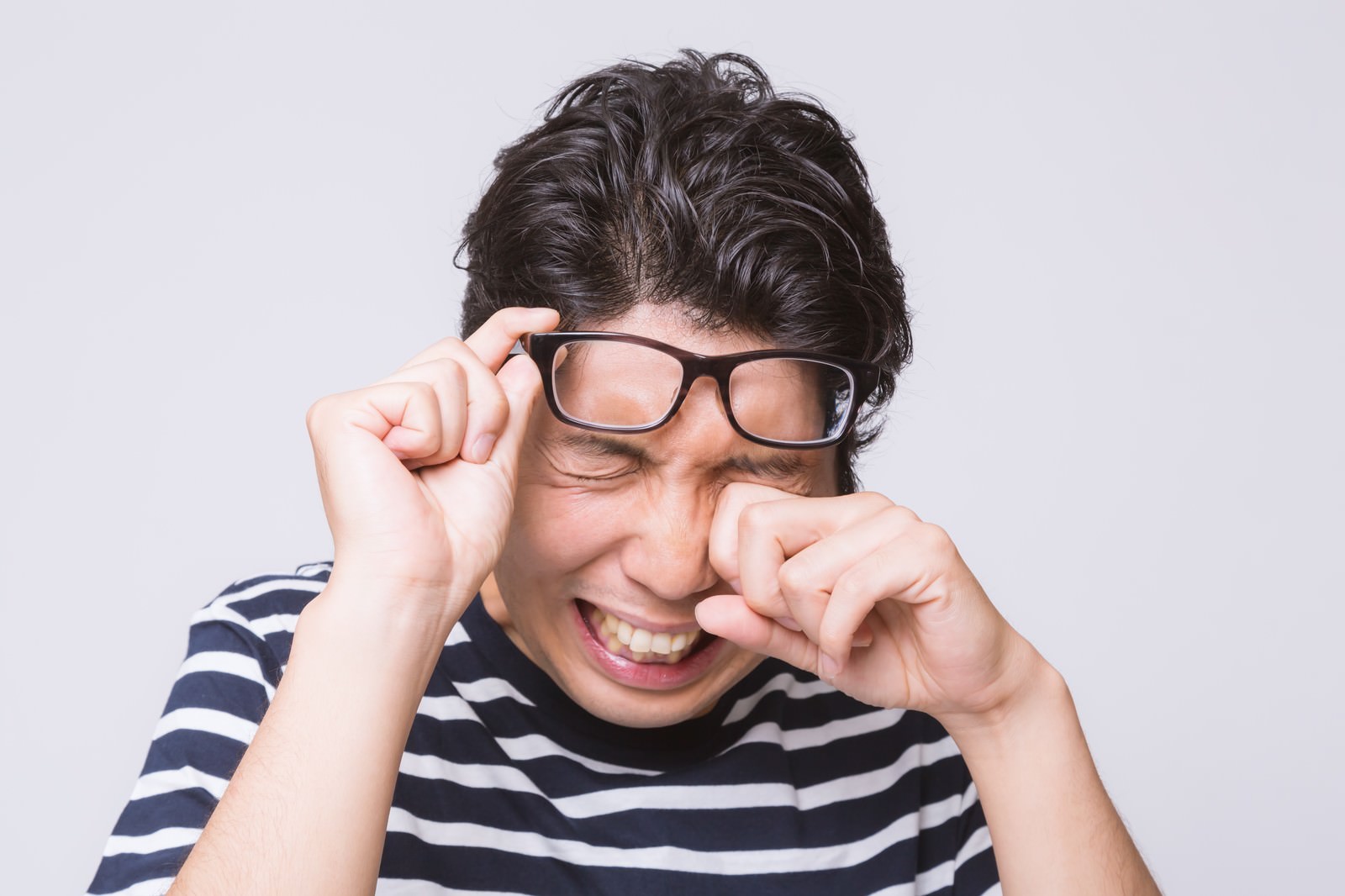 眼鏡を押し上げて目をつぶる男性がパソコン疲れで涙ぐむ［モデル：紳さん］