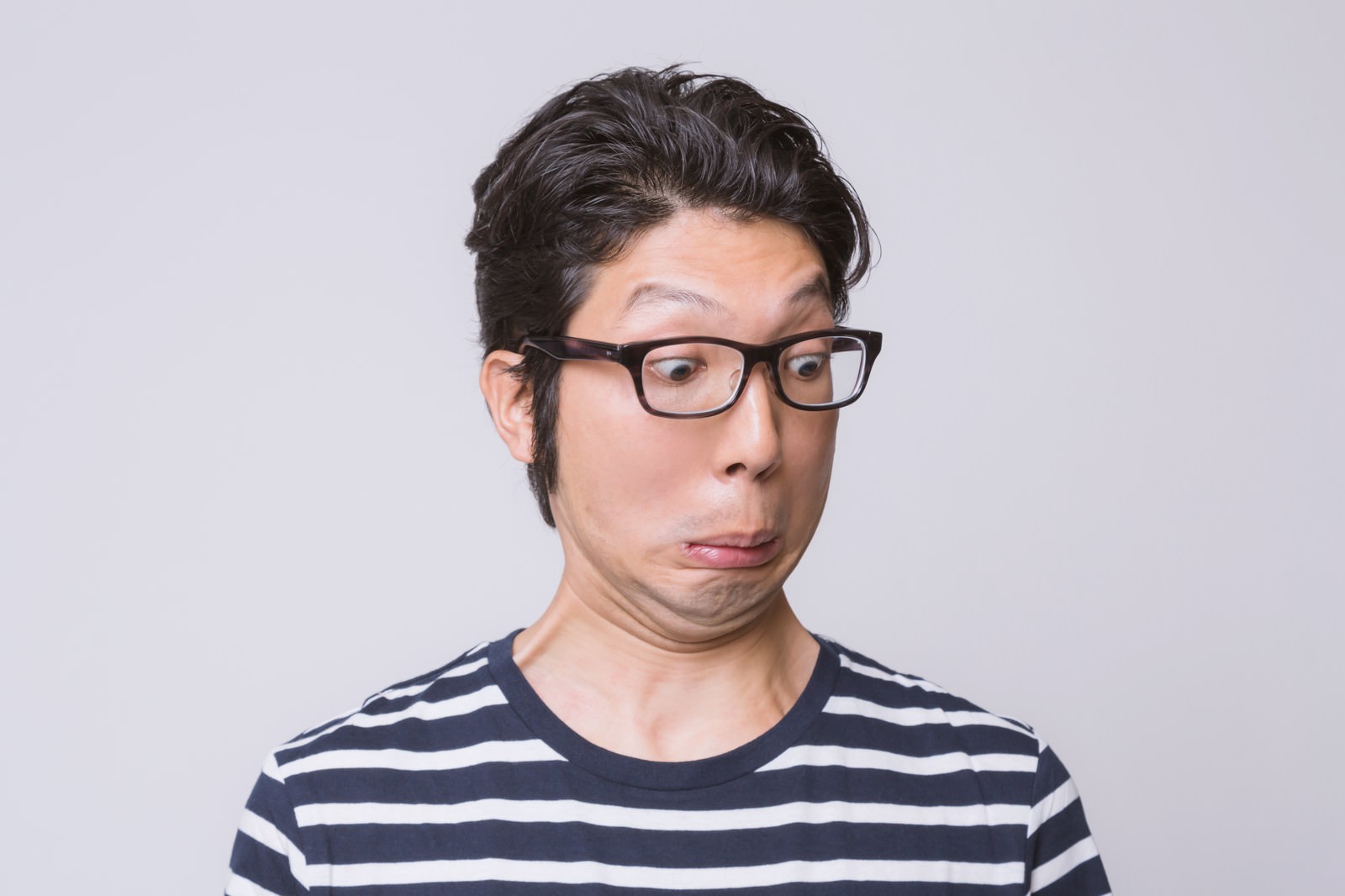 黒縁眼鏡をかけ驚いた表情の男性がボーダーシャツで横向きで写る［モデル：紳さん］