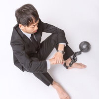 足枷と鉄球につながれた会社員の写真