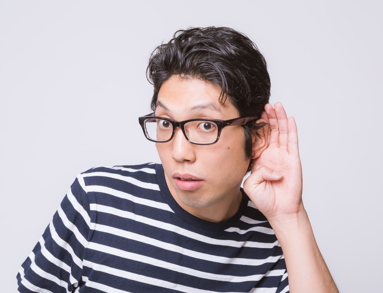 眼鏡をかけた男性が耳に手をあてて聞く［モデル：紳さん］