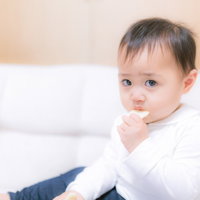 お菓子をあげたら泣き止んだ白い服の赤ちゃんの写真