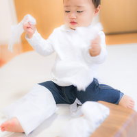 床に座って白いティッシュを散らかす白い服と青ジーンズの子供の写真