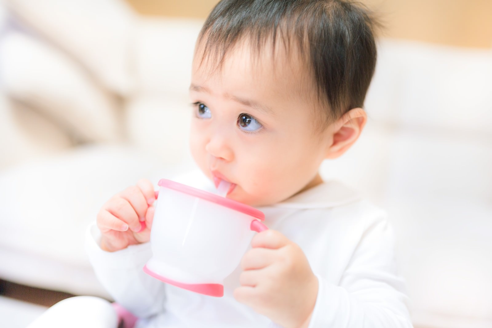 ストロー付きカップを口に当てて飲む幼児［モデル：Lisa］