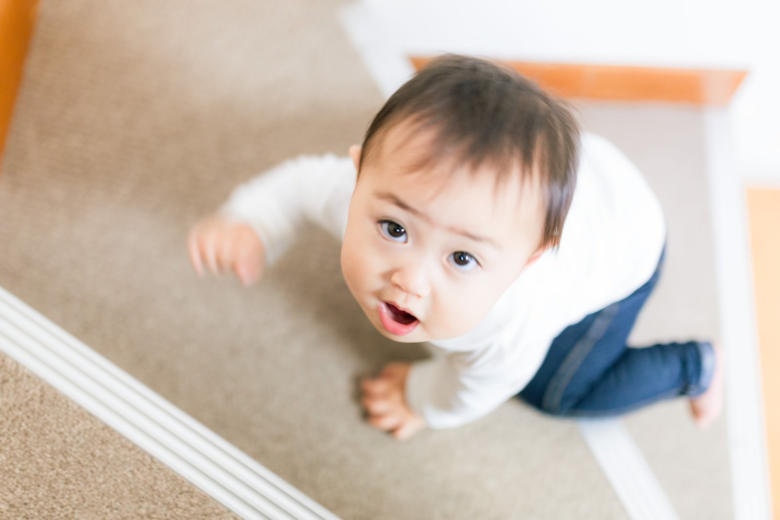 室内の床で上を見上げて口を開ける幼児［モデル：Lisa］