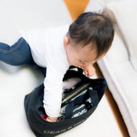 白いソファで黒いDEAN & DELUCAバッグの中を覗く幼児の写真