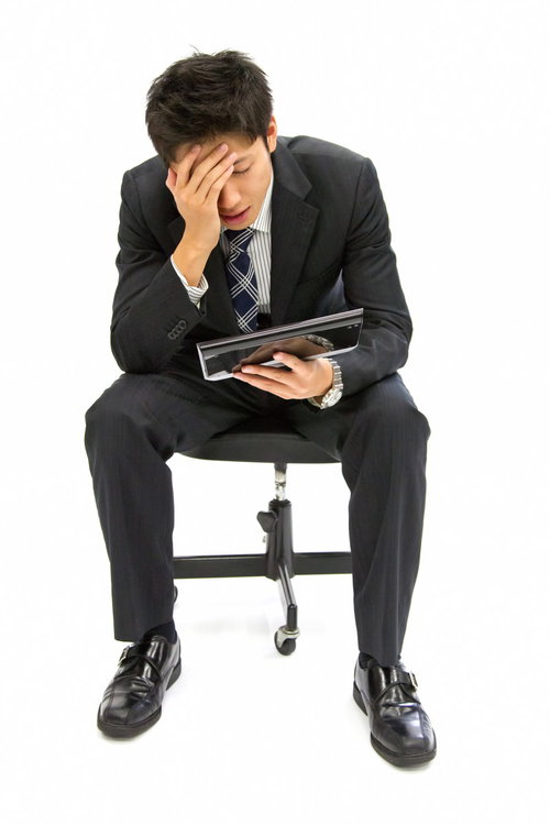 白い背景の前でタブレットを手に考え込むビジネスマン