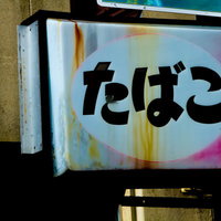 色あせて文字が読めなくなった朽ちたたばこの看板の写真