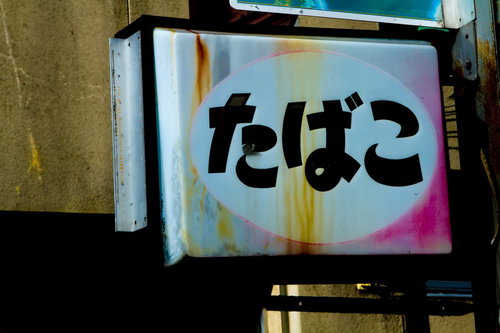 色あせて文字が読めなくなった朽ちたたばこの看板