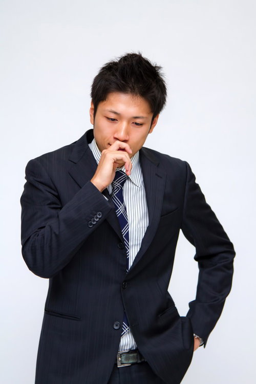 白い背景の前でポケットに手を入れて考え込む男性