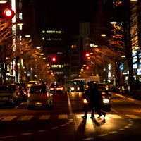 夜の大通りの横断歩道を渡る人々のシルエットの写真