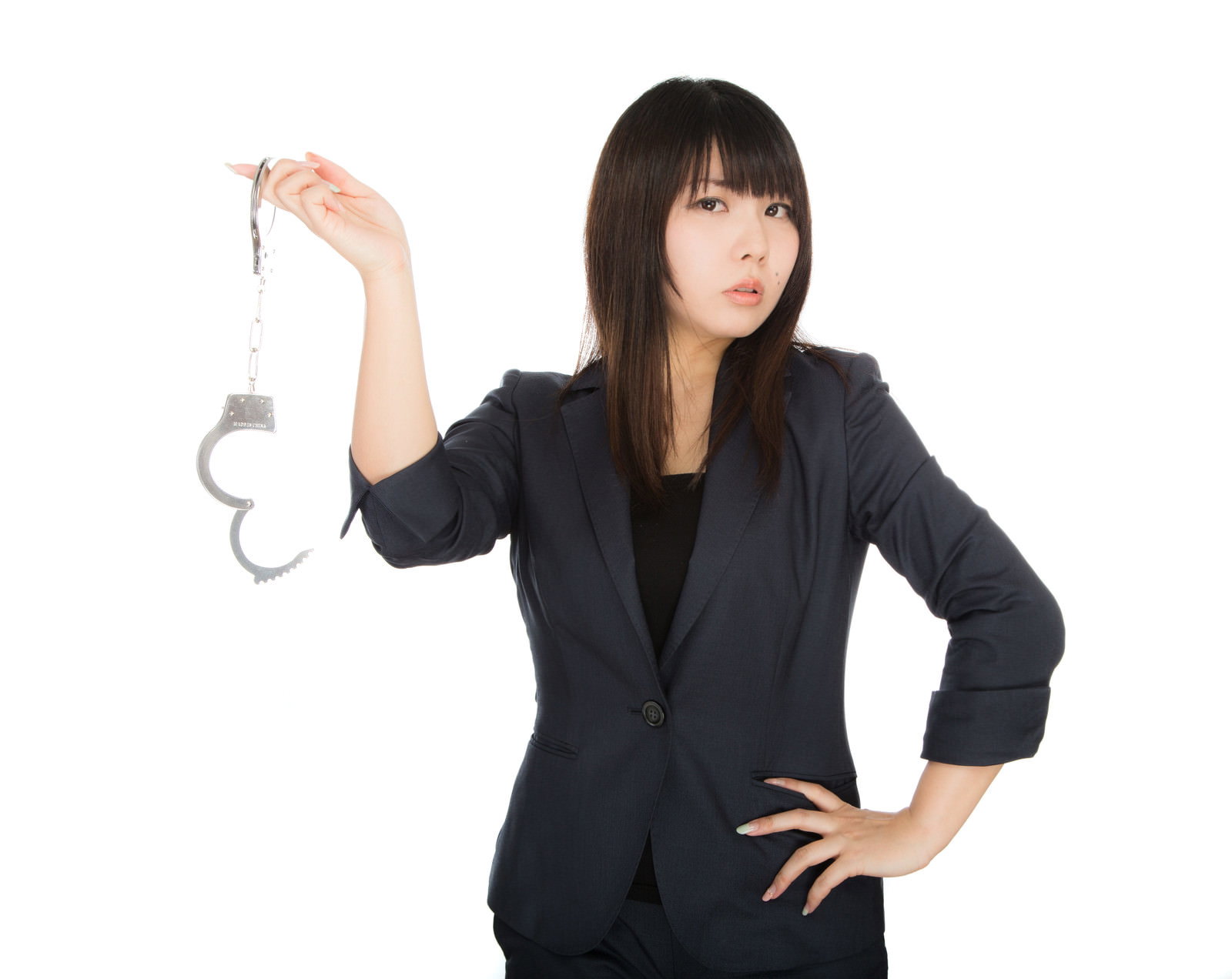 黒いジャケット姿で手錠を高く掲げ、腰に手を当てて正面を向く女性［モデル：Lala］