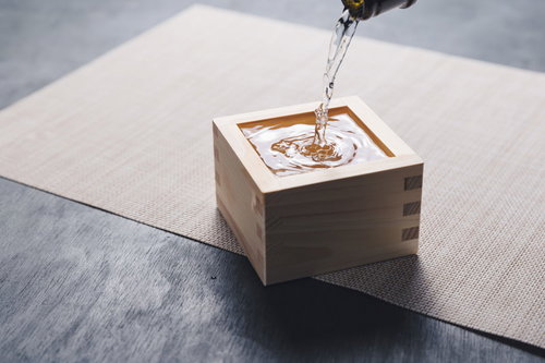升に溜まる透明な日本酒を白布の上に撮影した木製酒器