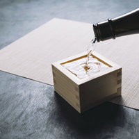 升いっぱいに注ぐ透明な日本酒の写真