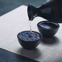 黒い徳利からお猪口に注がれた日本酒のの写真