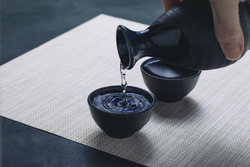 黒い徳利から青いお猪口に注ぐ日本酒