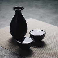 黒い徳利とお猪口になみなみの日本酒の写真