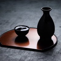 逆光で黒くシルエットになった徳利とお猪口の写真