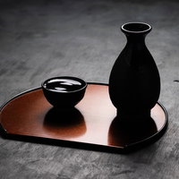 木製のお盆に置かれた黒い徳利とお猪口の日本酒器の写真