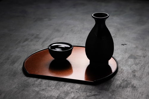 木製のお盆に置かれた黒い徳利とお猪口の日本酒器