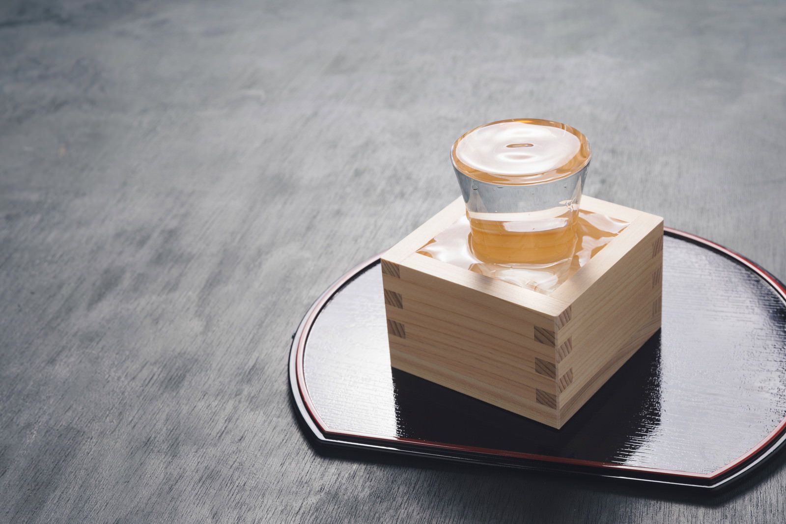 木製の升に日本酒がなみなみと注がれたもっきりが受け皿の上に置かれている