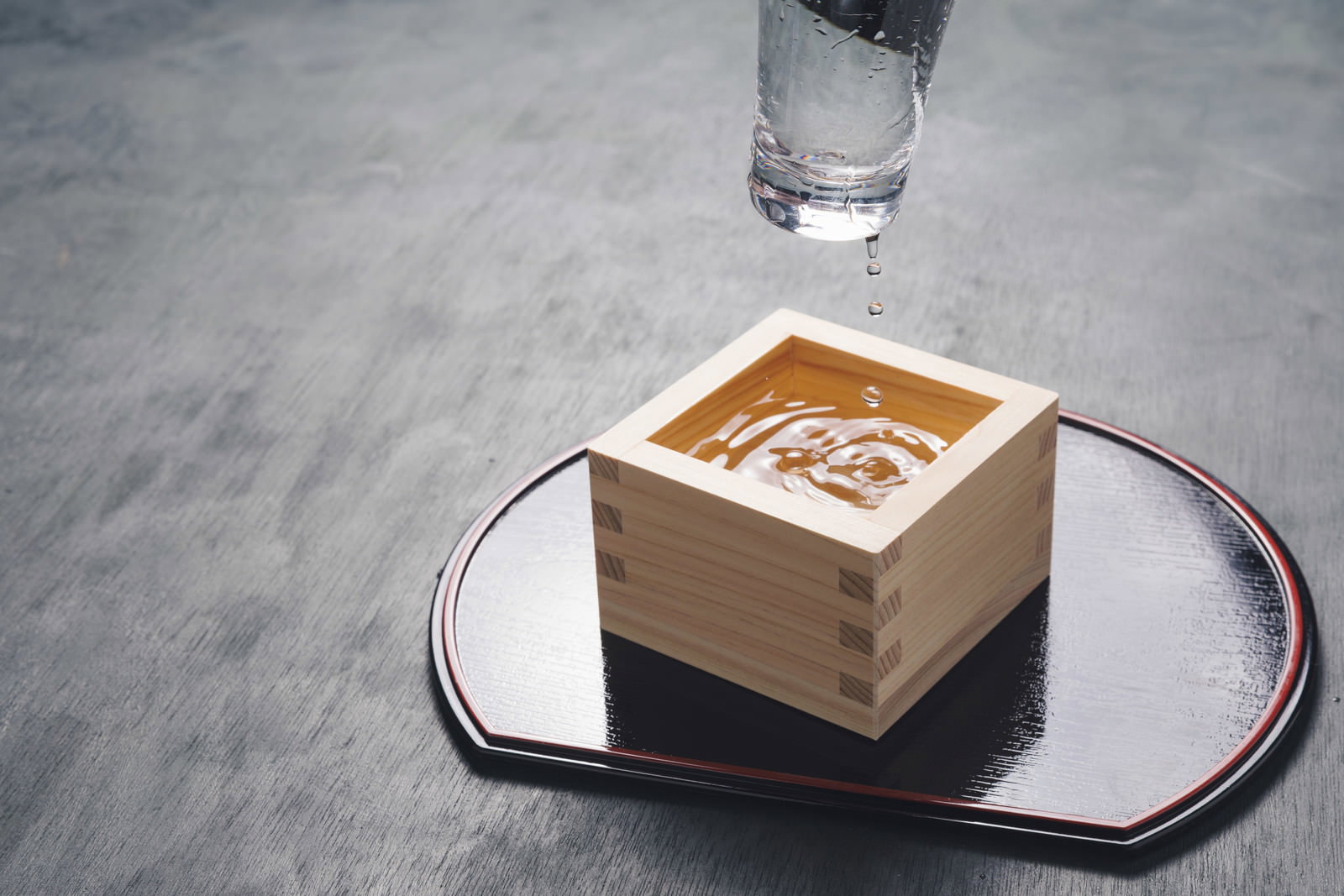 グラスから升に日本酒が注がれる瞬間
