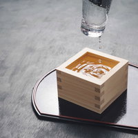 木製の升からグラスを上げて乾杯する瞬間、日本酒ともっきりの伝統的な飲み方の写真