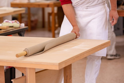 蕎麦打ち職人が武石観光センターでめん棒で巻き上げる生地