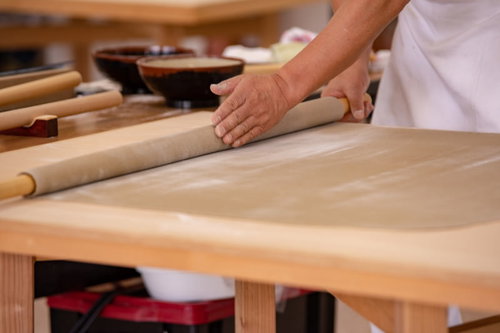 生地を丁寧に木製めん棒で巻き上げる蕎麦打ち職人