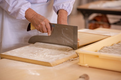 蕎麦の生地を包丁で切る職人（武石観光センター）