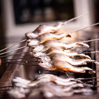 串に刺した鮎の塩焼きの写真