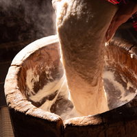 つきたての餅を持ち上げる返し手の手つきと杵の動きの写真