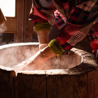 つきたての餅をなでるおばあちゃんの手と木製の臼の写真