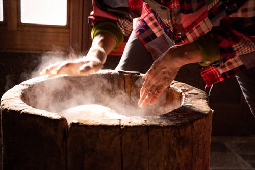つきたての餅から沸き立つ湯気、木製の臼で餅つき