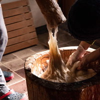 杵について伸びる餅つきの餅と湯気の写真