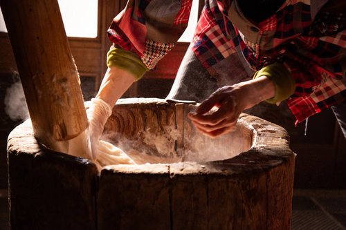 杵につく湯気のつきたて餅を剥がすおばあちゃんの手