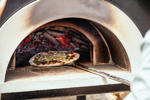 釜から取り出されるピザ