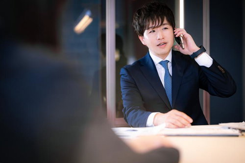 顧客先で電話確認するM&Aアドバイザーの男性