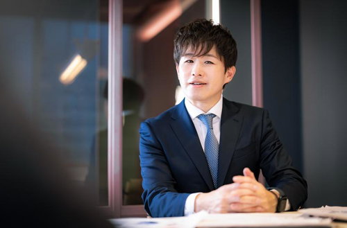 笑顔で相談に乗るM&Aアドバイザー、デスクでの営業打ち合わせ