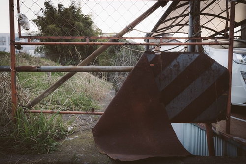 錆びて朽ち果てた進入禁止の門扉と廃墟の風景の写真