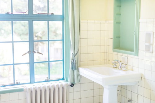 白いタイル壁と窓がある明るい浴室の洗面台