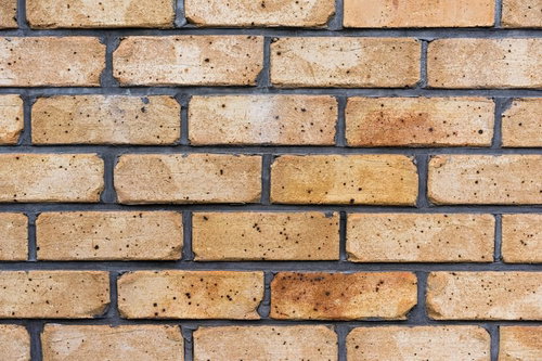 黒い穴や斑点が見える茶色いレンガが積まれた壁のテクスチャー