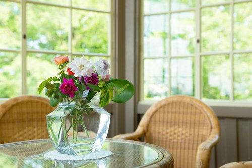 ガラステーブルに飾られたバラの花束と籐椅子